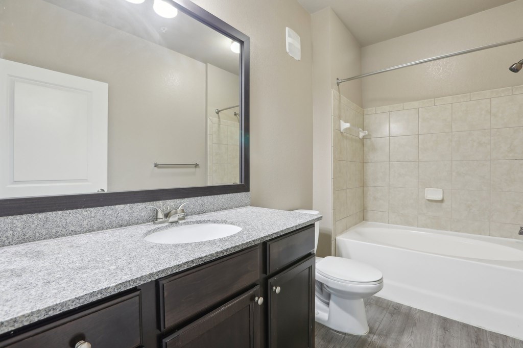 Model bathroom with a white toilet, sink, and bathtub.