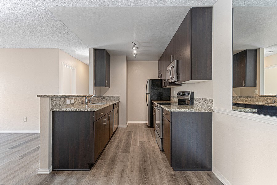 Model Kitchen with Dark Wood Cabinets and Wood-Style Flooring at Santa Fe Ranch Apartments located in Carlsbad, CA.