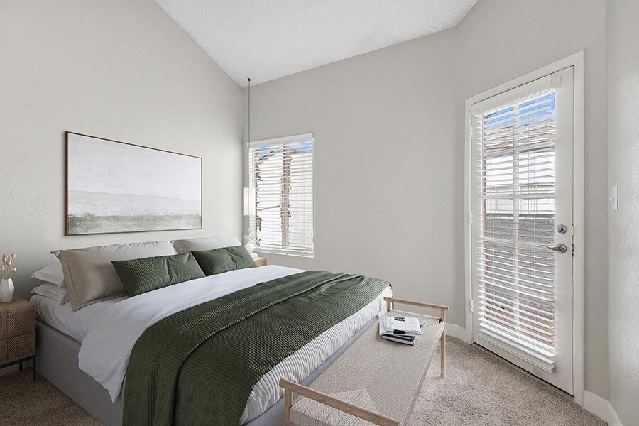 Model Bedroom with Carpet and Patio Accessibility at Crystal Creek Apartments in Phoenix, AZ.