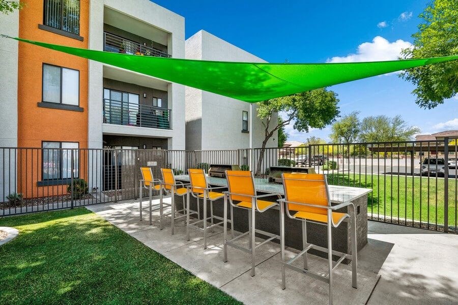 Outdoor BBQ Area with Furniture and Green Canopy at Harmony at Surprise Apartments in Surprise, AZ.