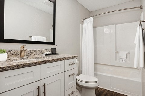 Model Bathroom with Wood-Style Flooring, White Cabinets & Shower/Tub at Park 2300 Apartments in Charlotte, NC.