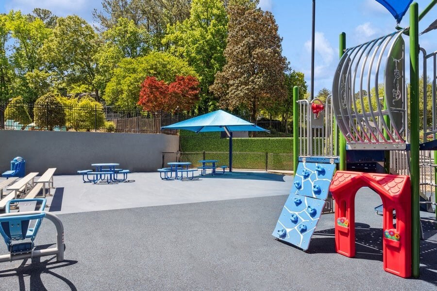Community Playground and Outdoor Picnic Tables with Blue Canopy at Dunwoody Village Apartments in Atlanta, GA.