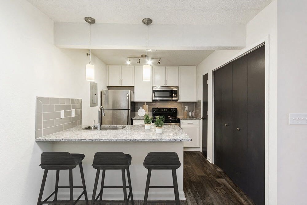 Model Kitchen with White Cabinets and Wood-Style Flooring at Grandstand Apartments in Marietta, GA.