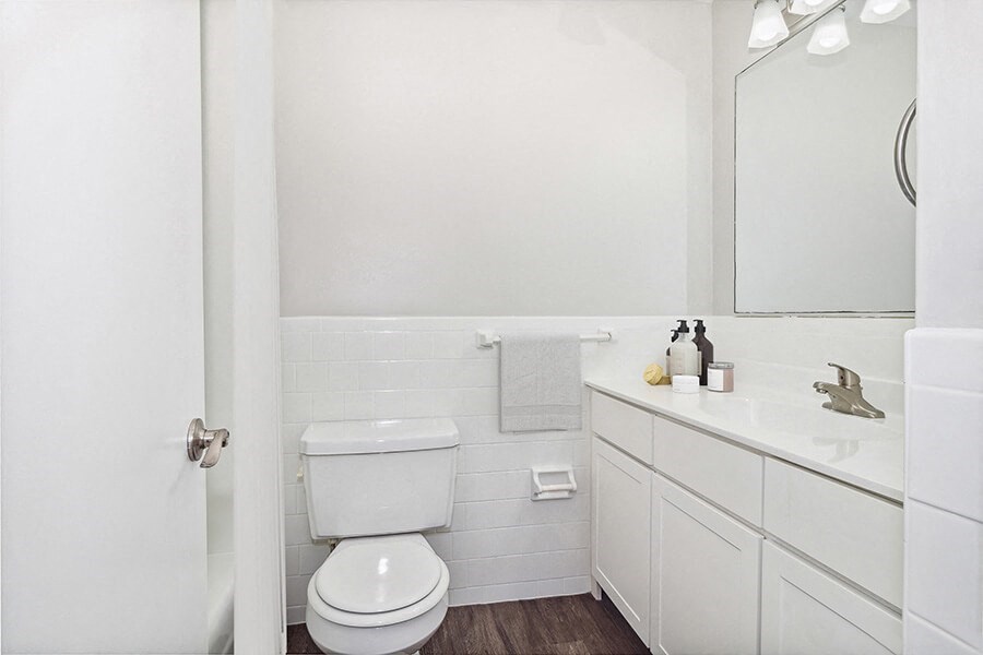 Model bathroom with a toilet, sink, and mirror  at Stone Ends apartments in Stoughton, MA