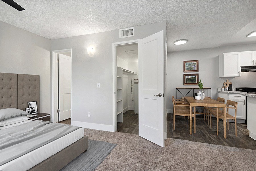 Model Studio Bedroom with Carpet and View of Dining Room at Stillwater Apartments in Glendale, AZ.