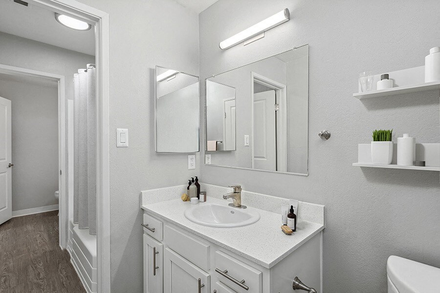 Model Bathroom with White Cabinets and Wood-Style Flooring at The Archer Apartments in Sacramento, CA.