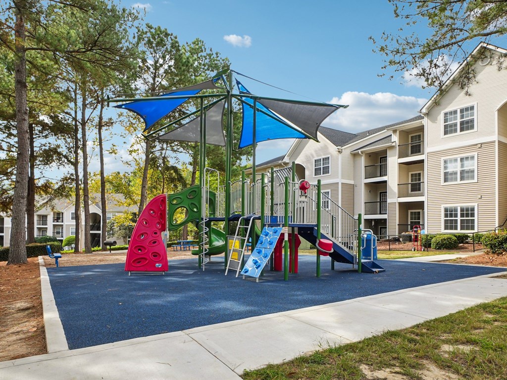 A playground with a blue shade structure and a slide.