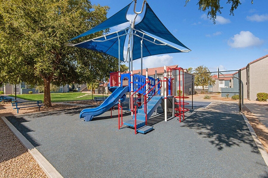 Community Playground with a Slide and Blue Canopy at Peaks on 4th Apartments in Avondale, AZ.