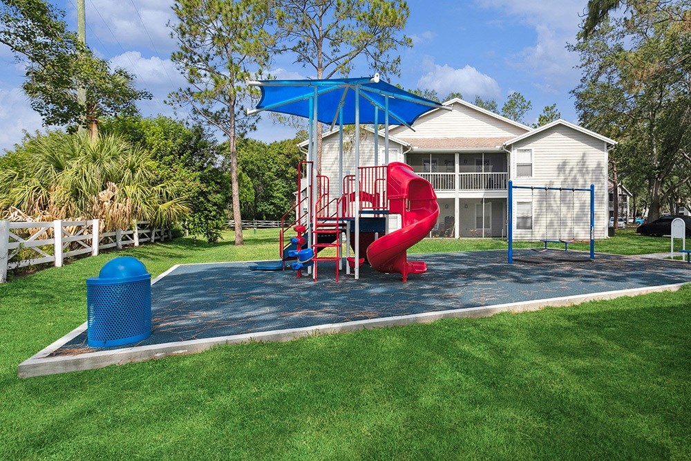 Community playground with a red slide and sun cover at Retreat at Crosstown Apartments