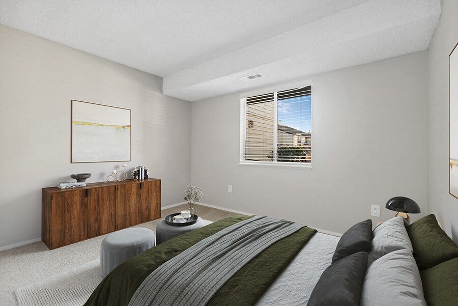 Model Bedroom with Carpet and Window View at Liberty Creek Apartments in Aurora, CO.