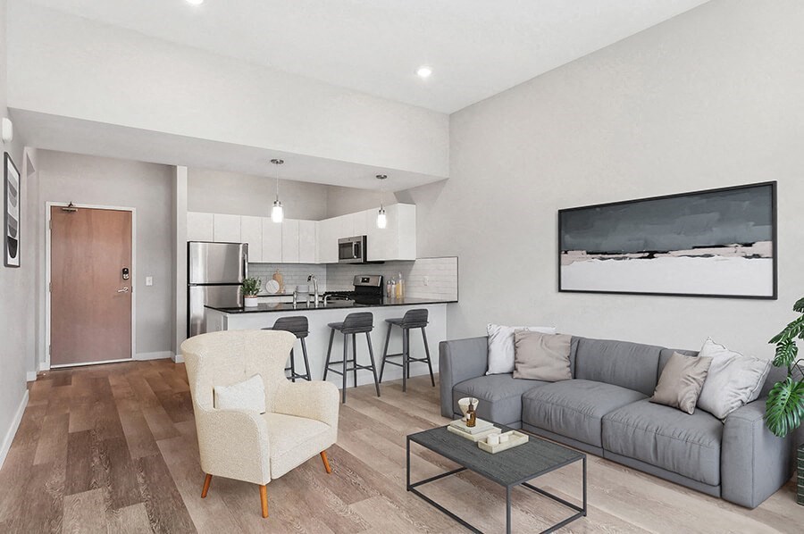 Model Living Room with Wood-Style Flooring and View of Kitchen at Seven Skies Apartments located in Sandy, UT.