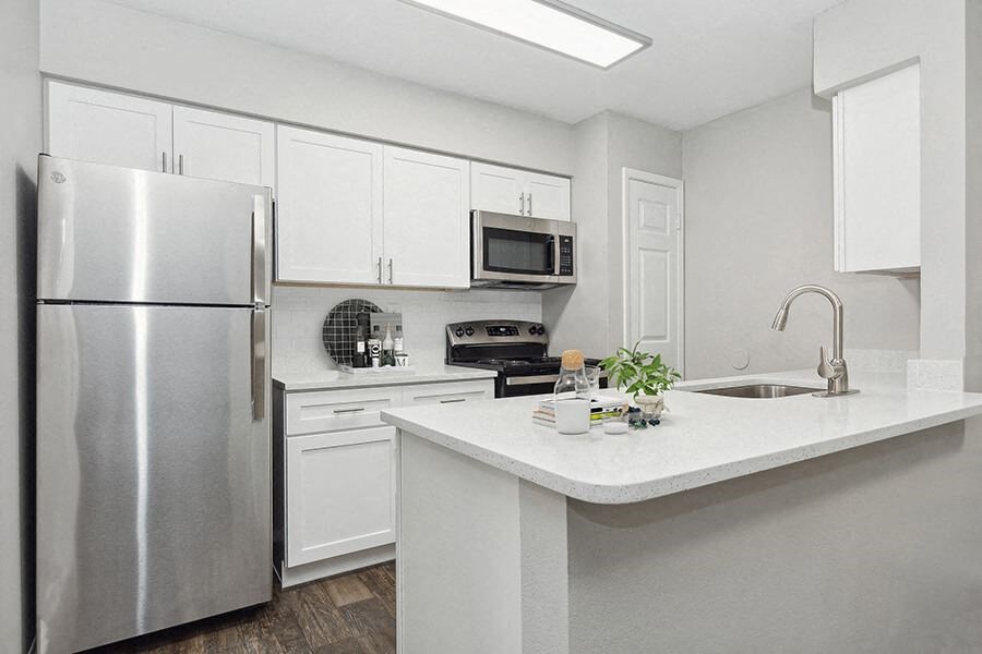 Model Kitchen with White Cabinets and Wood-Style Flooring at Grand Pavilion Apartments in Tampa, FL.