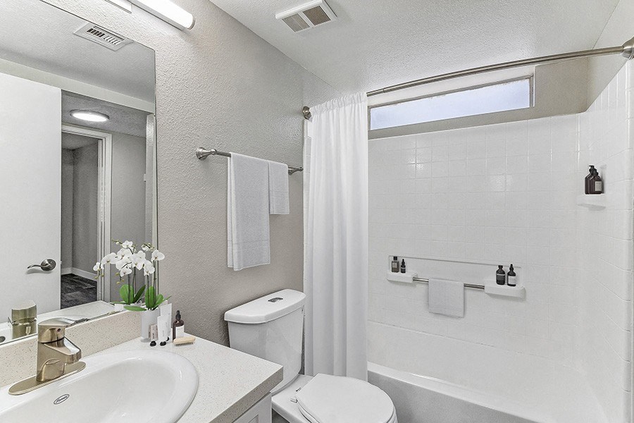 Model Bathroom with White Cabinets and Wood-Style Flooring at Meadow Ridge Apartments in Las Vegas, NV.