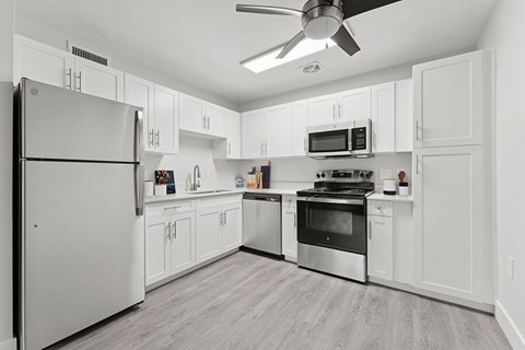 Model Kitchen with White Cabinets and Wood-Style Flooring at The Grove at Walnut Creek Apartments located in Walnut Creek, CA.