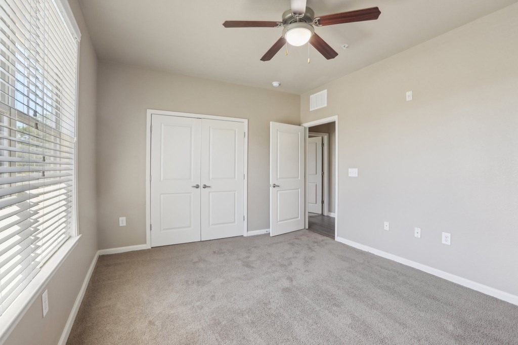 Model bedroom with a ceiling fan and two doors.
