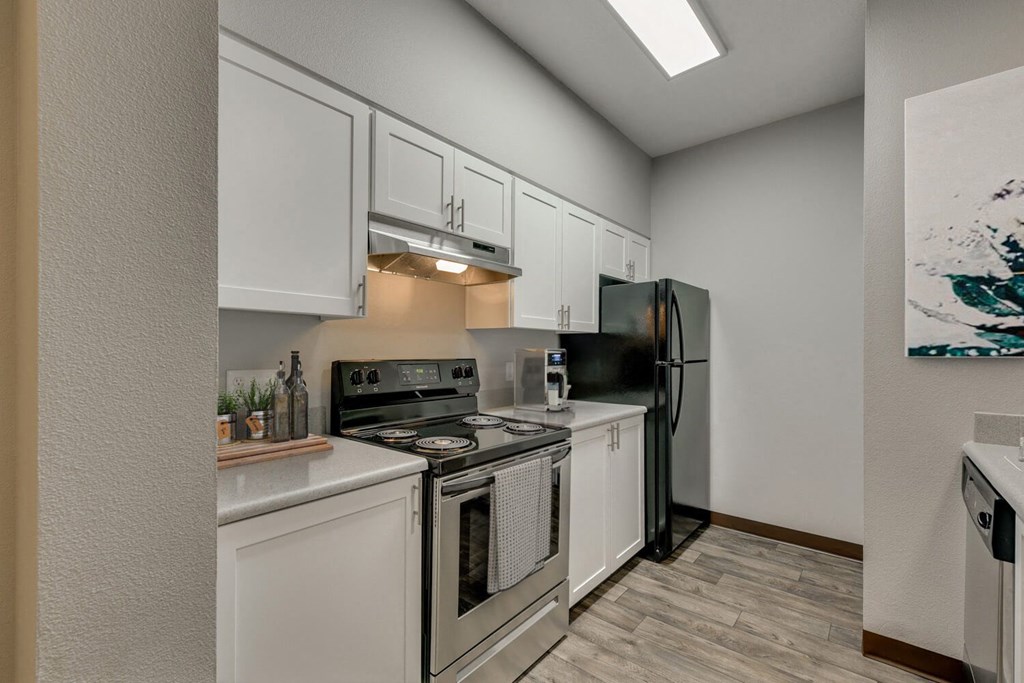 Model Kitchen with White Cabinets and Wood-Style Flooring at Landings at Morrison Apartments located in Gresham, OR.