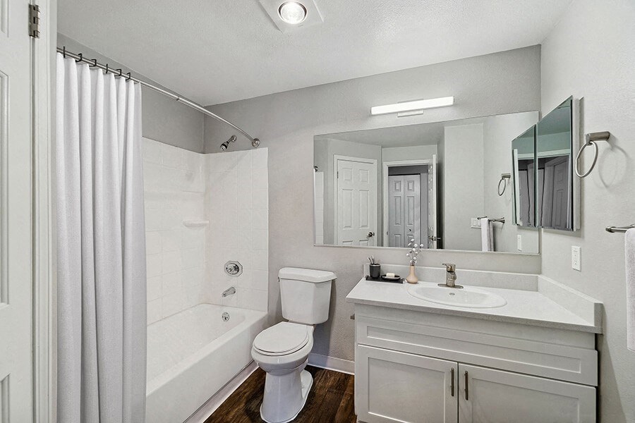 Model Bathroom with White Cabinets, Wood-Style Flooring and Shower/Tub at Central Flats Apartments in Kent, WA.