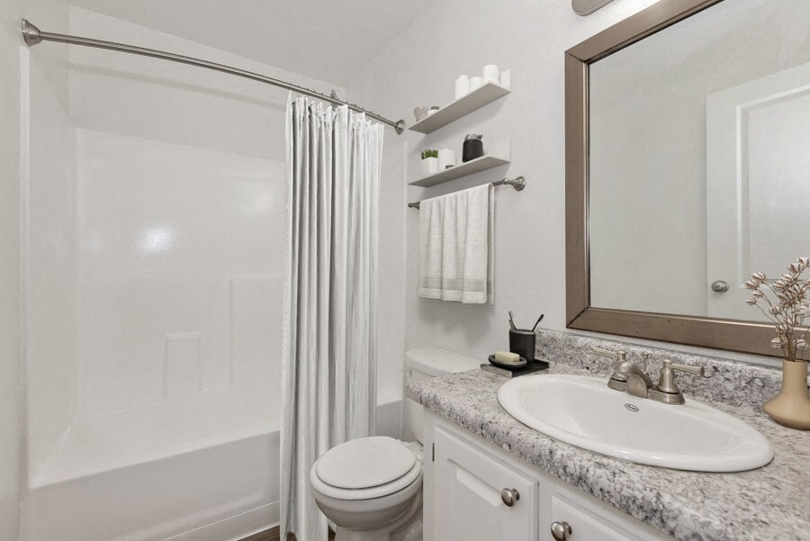 Model apartment bathroom with a shower toilet and sink and a mirror at Saratoga Ridge, Phoenix, AZ