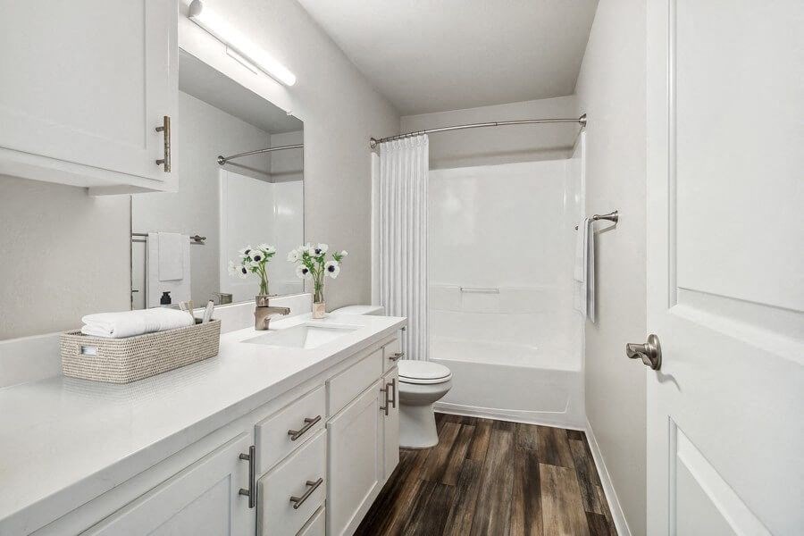 Model Bathroom with Bathtub/Shower, Wood-Style Flooring & White Cabinets at Forest Park Apartments in El Cajon, CA.