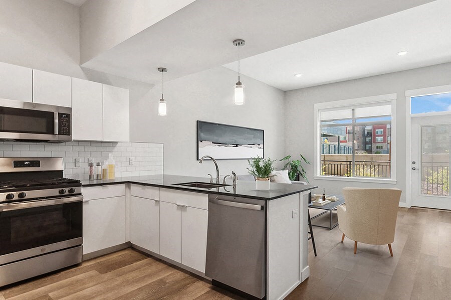 Model Kitchen with Wood-Style Flooring, White Cabinets and View of Living Room with Patio Accessibility at Seven Skies Apartments located in Sandy, UT.