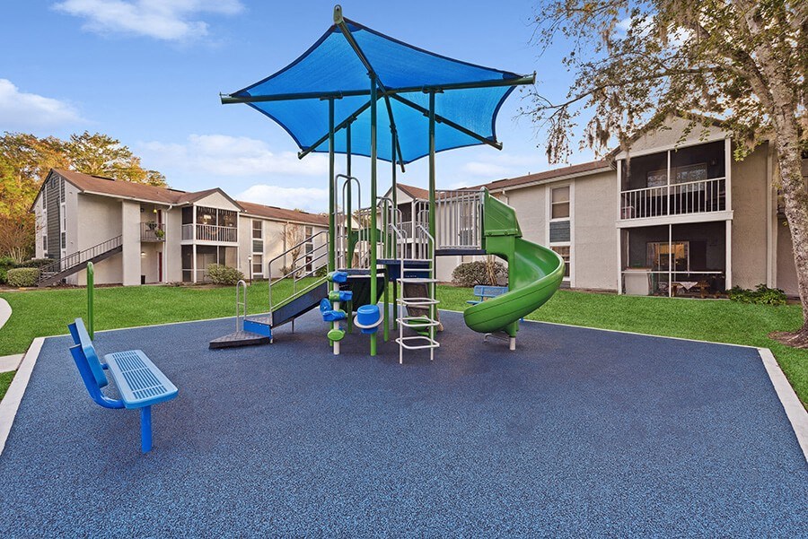 Community Playground with Slide and Blue Canopy at Vue at Baymeadows Apartments in Jacksonville, FL.