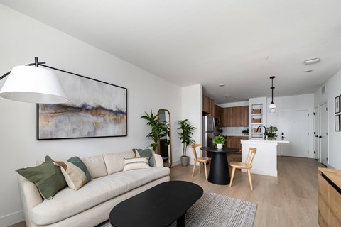 A modern living room with a white sofa, a black coffee table, and a painting on the wall.