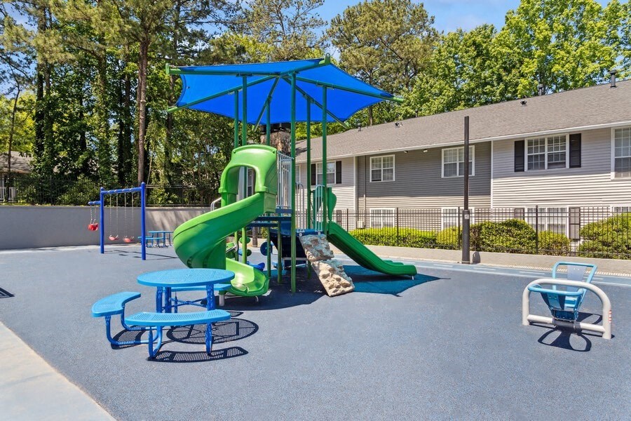 Community Playground with a Slide, Swing Set and Blue Canopy at Dunwoody Village Apartments in Atlanta, GA.