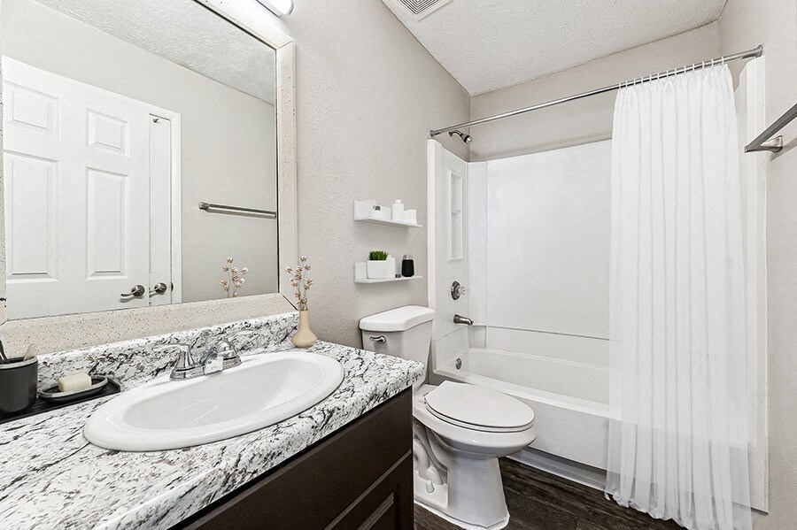 Model Bathroom with Dark Cabinets, Wood-Style Flooring and Shower/Tub at Paramont Apartments in Duluth, GA.