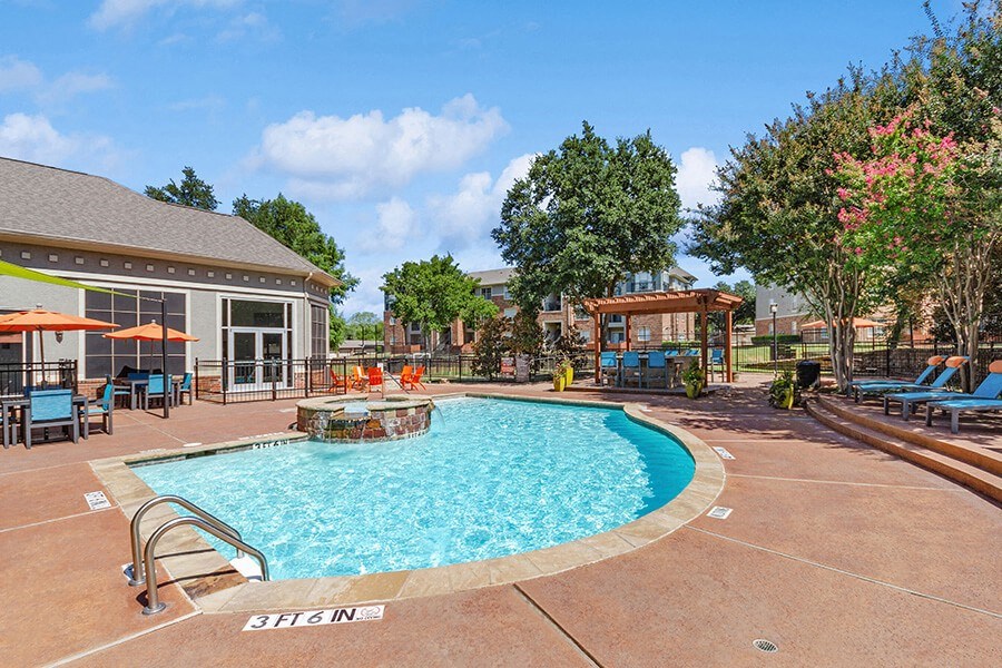 Community Swimming Pool with Pool Furniture at Belmont at Duck Creek Apartments in Garland, TX.