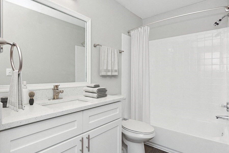 Model Bathroom with White Cabinets, Wood-Style Flooring and Shower/Tub at Grand Pavilion Apartments in Tampa, FL.