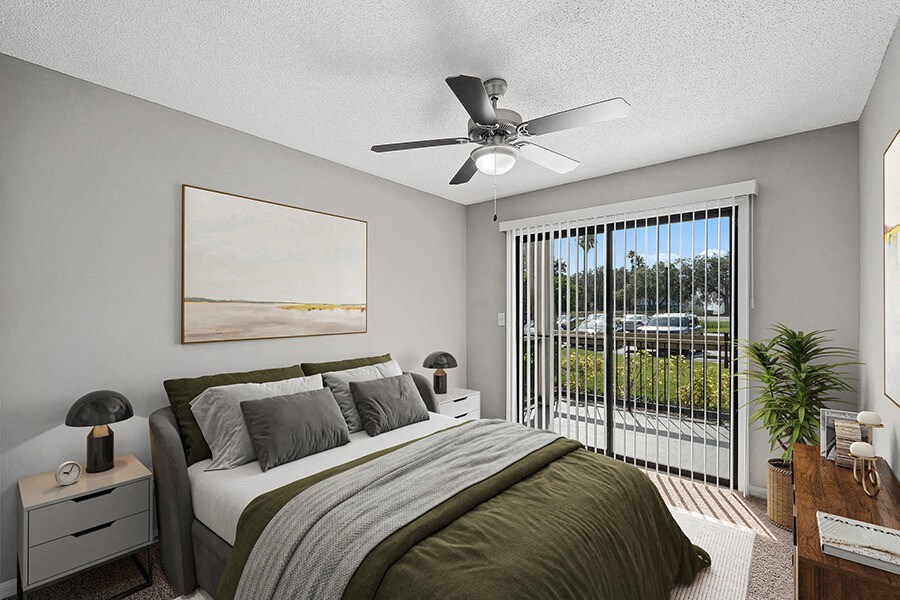 Model Bedroom with Carpet and Patio Accessibility at Fountains Lee Vista Apartments in Orlando, FL.