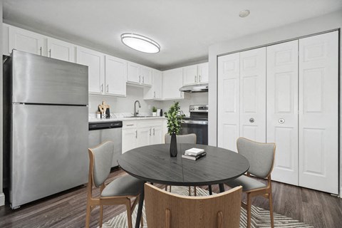 a kitchen and dining room with white cabinets and a stainless steel refrigerator