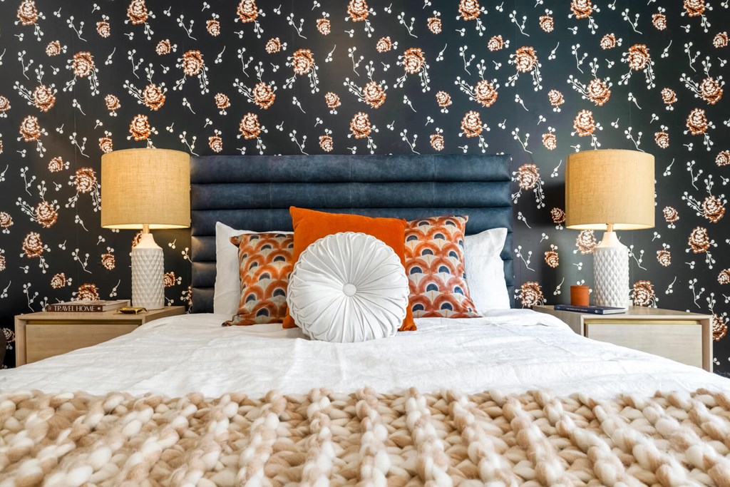 Model bedroom with blue walls and a bed with orange and white pillows