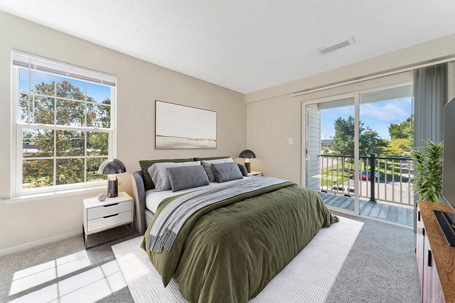 Model Bedroom with Carpet and Patio at The Commons at Haynes Farm Apartments in Boston, MA.
