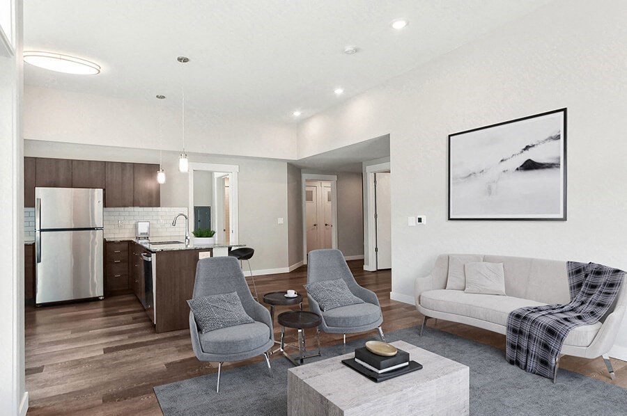 Model Living Room with Wood-Style Flooring and View of Kitchen at Seven Skies Apartments located in Sandy, UT.