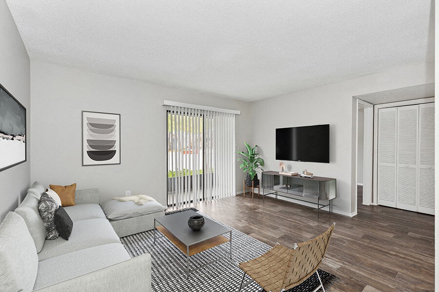 Model Living Room with Wood-Style Flooring and Patio Accessibility at Grand Pavilion Apartments in Tampa, FL.