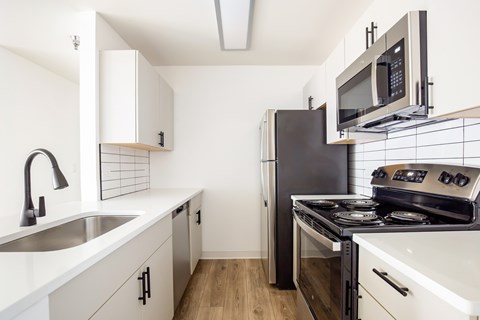 A kitchen with a black refrigerator and stove top oven.