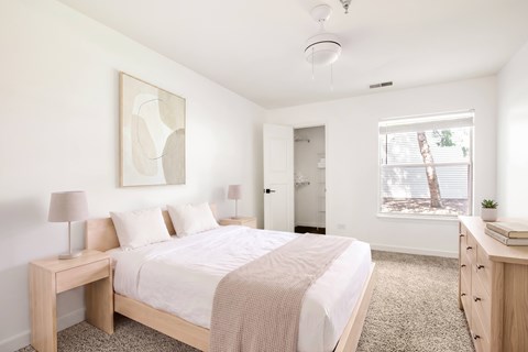 Model bedroom with a bed, nightstand, and a painting on the wall.