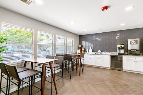 A woman is standing in a kitchen with a table and chairs.