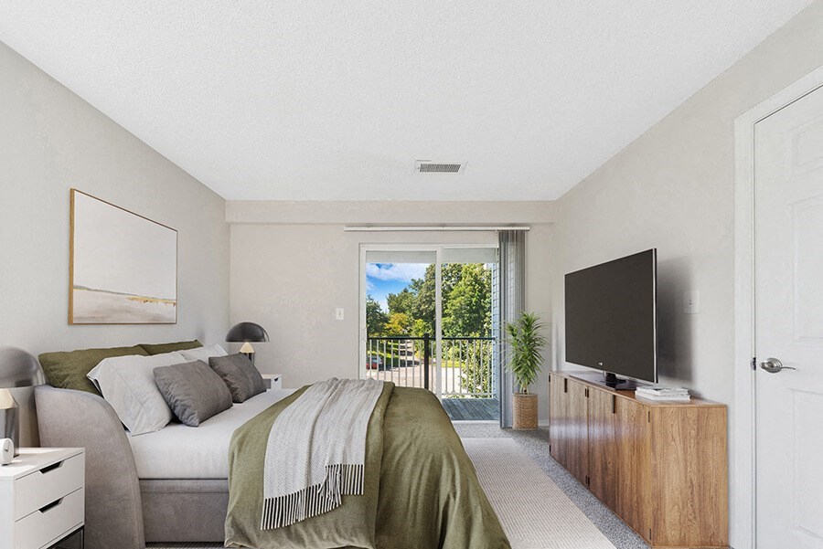 Model Bedroom with Carpet and Patio at The Commons at Haynes Farm Apartments in Boston, MA.