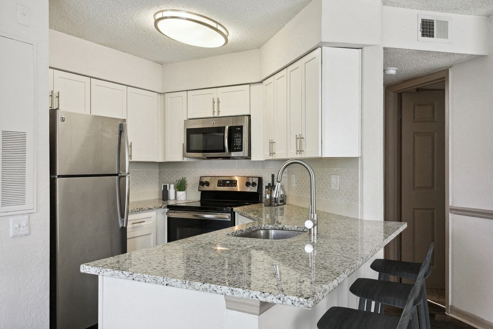 Model kitchen with white cabinets and a granite counter top at Retreat at Crosstown Apartments