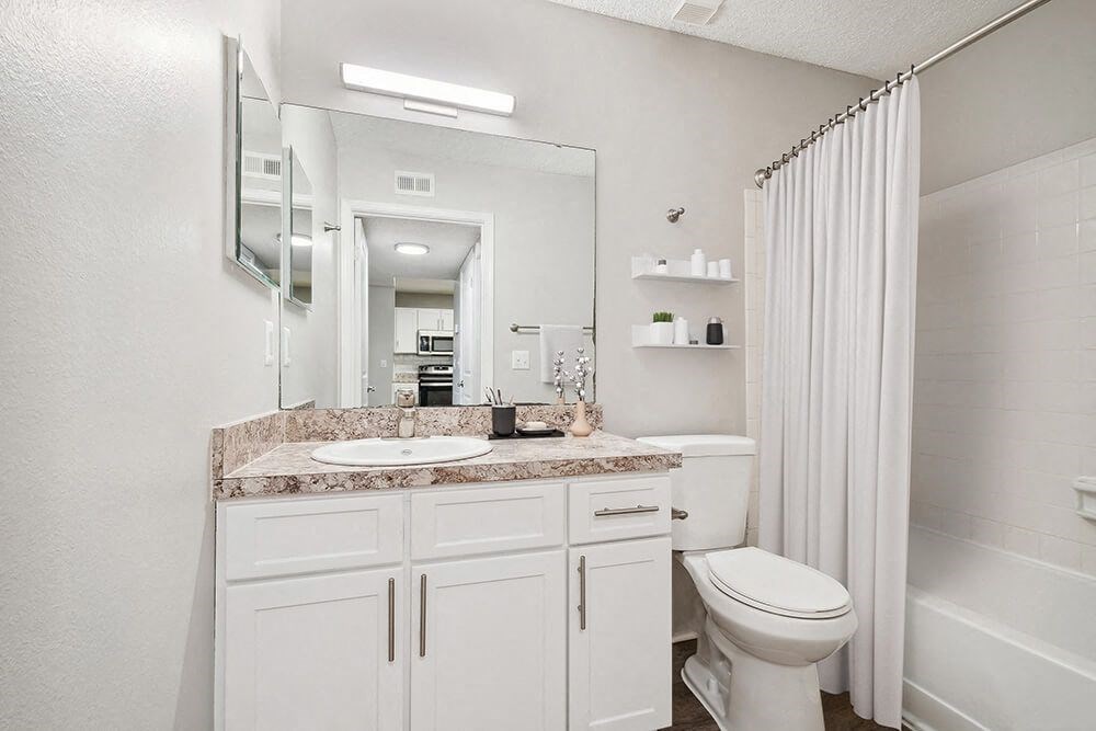 Model Bathroom with White Cabinets, Wood-Style Flooring and Shower/Tub at Westland Park Apartments in Jacksonville, FL.