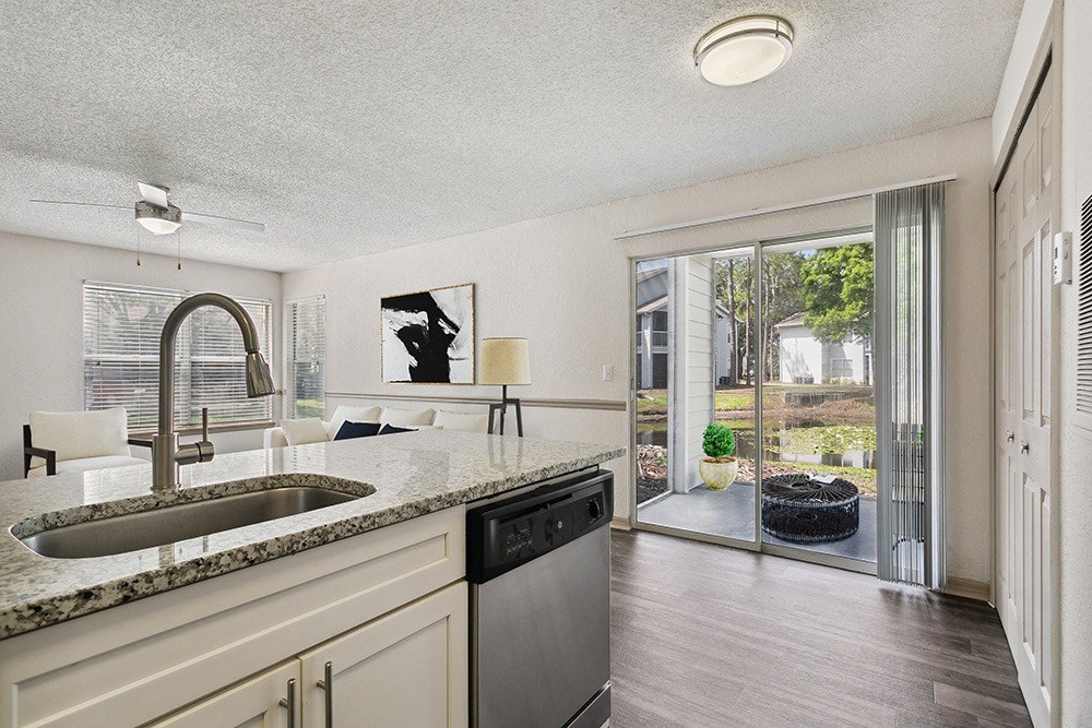 Model kitchen and living room with a sliding glass door leading to a patio at Retreat at Crosstown Apartments