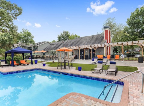 Two-Bedroom Apartments in Marietta, GA - Laurel Hills Preserve - A Swimming Pool With Blue Water, Lounge Chairs, Cabana Canopy, Patio Tables With Umbrellas, And A Clubhouse.