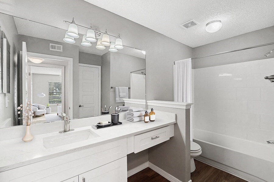 Model Bathroom with White Cabinets, Wood-Style Flooring & Shower/Tub at Fountains Lee Vista Apartments in Orlando, FL.