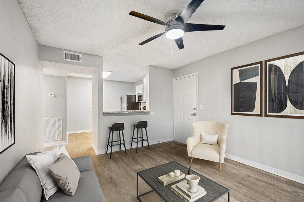 Model Living Room with Wood-Style Flooring and View of Kitchen at Westland Park Apartments in Jacksonville, FL.
