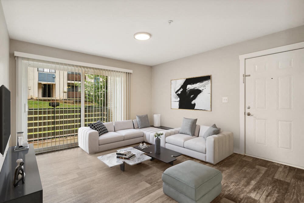 Model living room with a white couch and a coffee table in front of a large window with