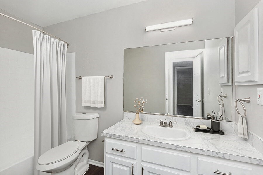Model Bathroom with White Cabinets, Wood-Style Flooring and Shower/Tub at Grand Pavilion Apartments in Tampa, FL.