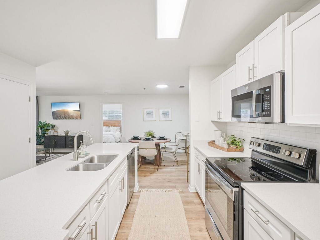 A modern kitchen with white cabinets and stainless steel appliances.