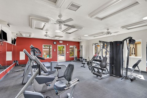 A gym with a variety of equipment including treadmills, weights, and exercise machines.